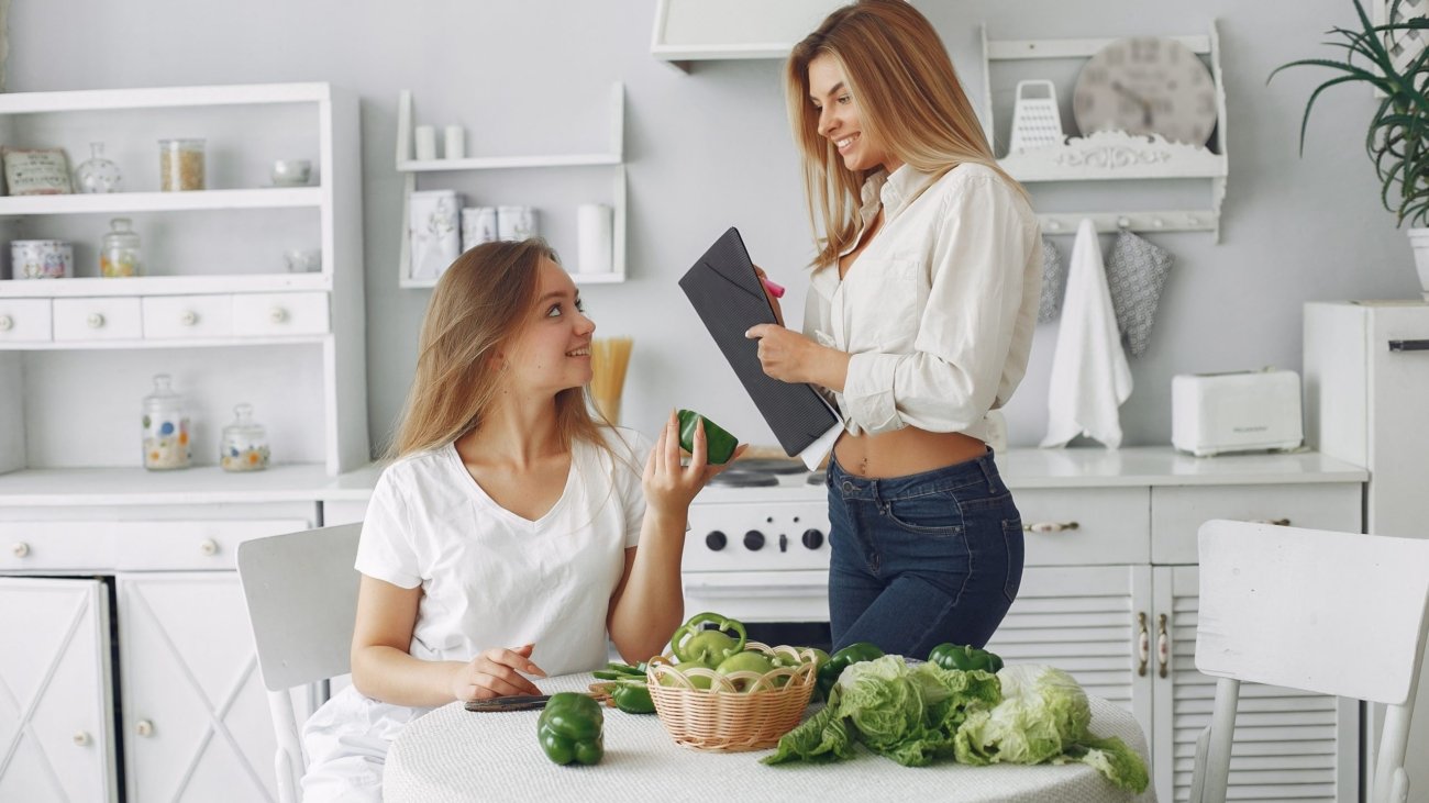 Beautiful and sporty girls in a kitchen with a vegetables