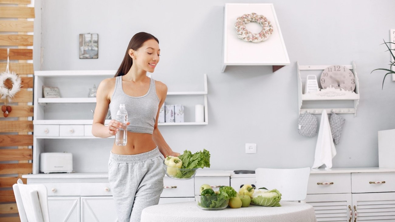 Beautiful and sporty girl in a kitchen with a vegetables